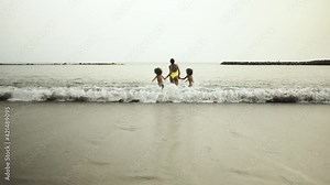 Happy African family running on the beach during summer holidays - Afro American people having fun on vacation time - Parents love and travel lifestyle concept