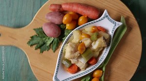 Boiled cod with potatoes, celery and carrots. Close-up of plate ready to cook, on green wooden background