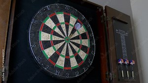 A dart hitting a bullseye on a dart board. Slowed to half speed