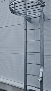 fire ladder leading to the roof of the hall is secured by a grille in the lower part of the protective grille. white metal warehouse walls. galvanized iron and a pipe for connecting fire hose, hatch