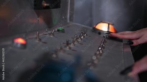 A woman with long black nails presses buttons on an old factory control panel. Close-up control panel. The control panel is at the factory.