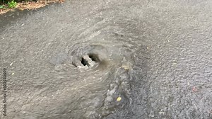 Drain manhole in stone almost full of water during heavy rain, creating a vortex Stock Video