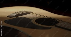 A shadow slowly darkens the body of the acoustic guitar