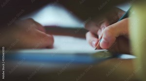 Little boy does homework, writes useful information. A child writes letters in a school notebook. On the table are books, notebooks and pencils. Distance Learning, E-Education, Homeschooling Concept.