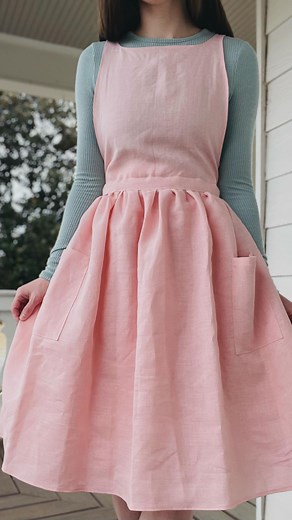 Brittany | A Catholic Convert on Instagram: "Introducing a lovely pink linen wrap dress pinafore for St Philomena. Like my other recent creations, this pattern is inspired by the wrap dresses of the 1950s and 1960s. So versatile and nursing friendly, this wrap style can be worn as a dress (as shown in this reel) as well as a forager’s apron where the straps are tied at each hip, allowing perfect nursing access and also room for growing baby bumps. St Philomena is a special saint to my heart, but
