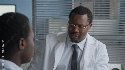 African American male doctor conducting physical exam by palpating patient shoulders to assess muscle tension, alignment, or joint issues during clinical visit