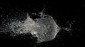 Super slow motion ball bursts with splashes of water. On a black background. High quality FullHD footage
