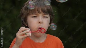 Little Boy Blowing Soap Bubbles Having Fun Playing Outside, Child Innocence and Curiosity. Boy Kid Blowing Soap Bubbles in Park, Garden and Nature, Having Fun, Joy and Childhood Development, Freedom.