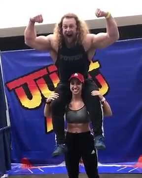 Strong girl lifts a big guy on her shoulders