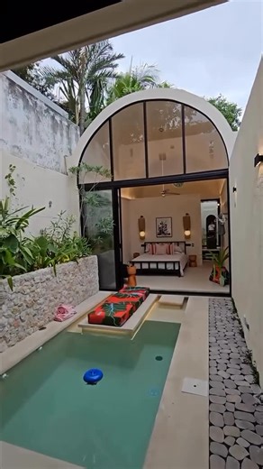 MODERN ARCHITECT MAGAZINES on Instagram: "Minimalist from the outside, but a true architectural marvel on the inside! ✨ This fully integrated house redefines open concept living by connecting the main spaces kitchen, living area and bedroom through a central pool. It’s a bold and brilliant use of space that promotes natural light and a seamless indoor & outdoor flow.🍃 We love how the use of natural light, neutral tones and organic materials results in a serene, harmonious space. What do 