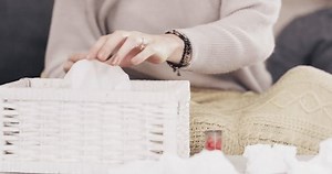 Sick couple, tissue and blowing nose on sofa for allergy, sinus or flu in living room at home. Man and woman with cold, infection or sneezing on couch from virus, disease or illness together at house