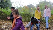 He's slow motion static front view of three children throwing leaves...