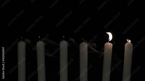 Six candles with flames are placed in a row on a dark background. Then, they blow out one by one.