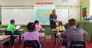 Teacher passing out papers to class