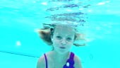 A 10 year old girl swimming with her eyes open underwater. She swims...