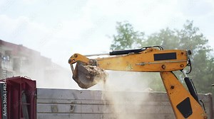 Digger excavator working and loading dust sand material rock loading a truck in slow motion