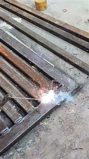 welding process of square steel pipes to create a metal frame with sparks and intense bright light