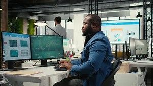 Black businessman correcting his bad posture at the workstation, dealing with back and neck muscle pain due to intense work. Administrator solving tasks for productivity and efficiency. Camera A.
