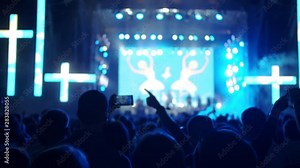 Night iconic concert. People cheer move and clap their hands in unison against the strobing stage lights.