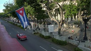 Classic american cars on the street in Havana seen from above, cuban flag in La Habana, Cuba