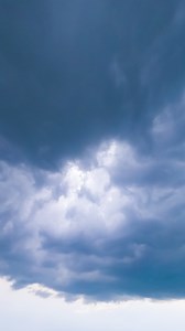Cloud mass moving around the sky. Dark clouds spreading in the sky. Timelapse low angle view perspective. Vertical
