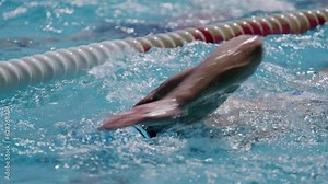 Close-up shot of a muscular professional swimmer swimming in a clean and luxurious pool. Slow motion how a man with toned body swimming professionally in butterfly style. Healthy lifestyle concept
