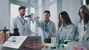 Professional team of scientists perform research in medical laboratory mixing chemical liquids using lab tools cooperating. Multi-race people. Pharmacy concept.