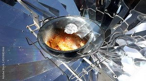 Cooking with sun energy, parabolic solar oven in the middle of cooking a dish thanks to solar energy