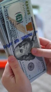 Vertical. A stack of crisp, dollar bills, held in capable hands. Man counting paper money. A cascade of American currency. A lot of dollars. A close-up view of US banknotes. Businessman counts banknot