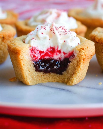 🍓🍰 Raspberry Cheesecake Cookie Cups Soft, Fruity & Bakery-Style Sweet These Raspberry Cheesecake Cookie Cups are tender sugar cookie cups filled with sweet raspberry jam and topped with a light, citrus-kissed cheesecake cream. Beautifully layered and perfectly portioned, they’re an easy yet elegant dessert for parties, holidays, or anytime you want something that looks impressive but is simple to make. Ingredients Cookie Dough • 2 cups all-purpose flour • 2 teaspoons baking powder • ½ teaspoon