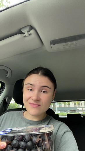 Enjoying Dark Grapes Inside a Car