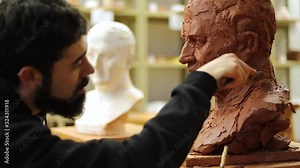Clay sculptor making a clay bust in an art studio