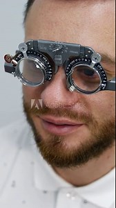 Handsome man at ophthalmology clinic. Special testing glasses with replacable lenses for vision correction on a male patient. Vertical video