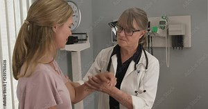 Senior woman doctor testing range of motion on injured arm of Caucasian female patient. Appointment with primary care physician or specialist for musculoskeletal injury. Slow motion 4k