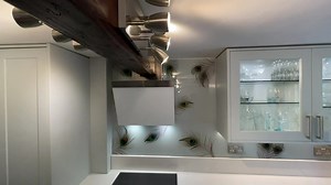 🦚🦚🦚 This printed peacock splashback has added a soft, elegant touch to this kitchen. It looks lovely against the rustic wooden beams and shaker style cabinets. Our peacock design can be customised in backing colour and feather size and layout to fit perfectly into your kitchen. Visit our website to enquire about a quote today: https://www.creoglass.co.uk/splashbacks/printed-splashbacks/printed-peacock-splashbacks | CreoGlass