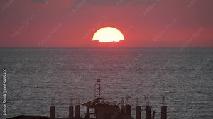 Red sun setting in the sea in Gaza with Israel flag in front, dramatic sunset footage