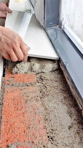 Worker installing ceramic tile on mortar over brick surface