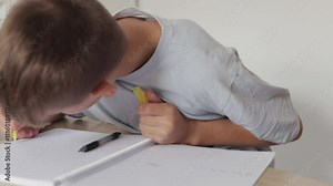 Young boy plays with a uv pen, creating invisible ink designs on a notepad and revealing them using the pen's integrated uv light