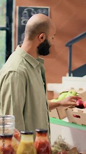 Vertical video Smiling client looking to buy spices from bulk products section, zero waste eco store with healthy food alternatives and natural produce. Young buyer choosing bio pantry supplies.