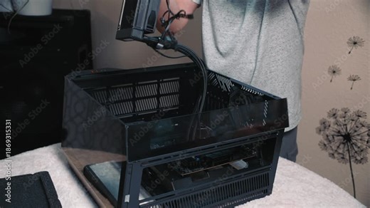 Installing liquid cooling system into compact computer case, personal PC build process showing close-up of male hands carefully placing radiator with fans inside a transparent chassis