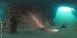 360 vr footage of the freediver. Man freediver swims underwater with torch and explores the West Papua region, Indonesia