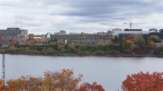 Drone footage tracking along the Ottawa River shoreline featuring government buildings and vibrant orange and red autumn trees and National Research Council of Canada.