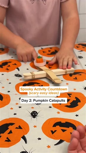 Day 2 of the Spooky Activity Countdown! 🎃 Five days of easy Halloween activities you can actually pull off. These pumpkin catapults are quick to build and so much fun for toddlers and preschoolers. You only need craft sticks, rubber bands, and a bottle cap — and they’ll stay busy launching for ages. Save this one for your next play day! #HalloweenActivities #PumpkinPlay #STEMPlay #ToddlerActivities #PreschoolFun #FallPlayIdeas | Play Made Easy