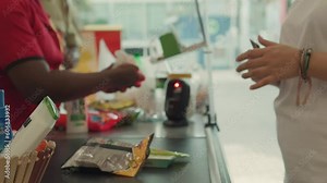 Cashier scanning goods on conveyor belt at the cash-desk of the supermarket.
