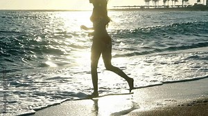 Slow motion jogging in morning on beaches in sea. Sand beach vacation running young woman if there is sea breeze.