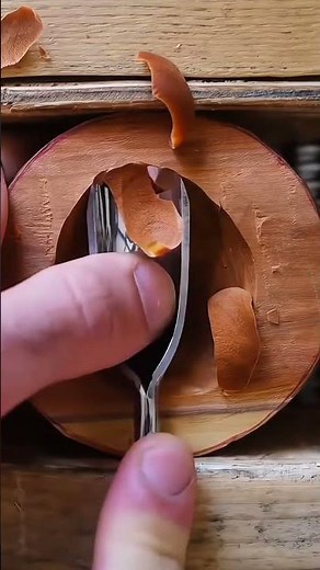Skilled hands carving smooth wooden surface using curved gouge tool