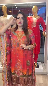 Kameez Style: Loose-fitting, long kurti with full sleeves. Print: Bold and colorful floral patterns in red, pink, purple, aqua blue, yellow, and soft peach. Neckline: V-cut with a small collar and button detailing down the front. Extras: Decorative tassels hanging from the hemline add a playful touch. Bottom Style: Wide-legged pants with an elastic waistband. Print: Matching floral design and colors as the top for a coordinated look. Hem: The bottom edge has a geometric printed border in red and