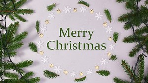 Merry Christmas text write in frame with snowflakes, pine branches and blinking lights. Stop motion