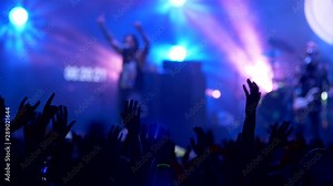 Crowd of people waving their hands in rythm of song on a rock concert. People as silhouette. Stage shining with blue color. Unrecognizable Singer and guitarist performing. 4K