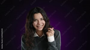 The girl is laughing hysterically, looking into the camera, unable to stop her laughter. She is on a purple background. High quality 4k footage